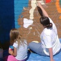 Teacher and pupil completing mural